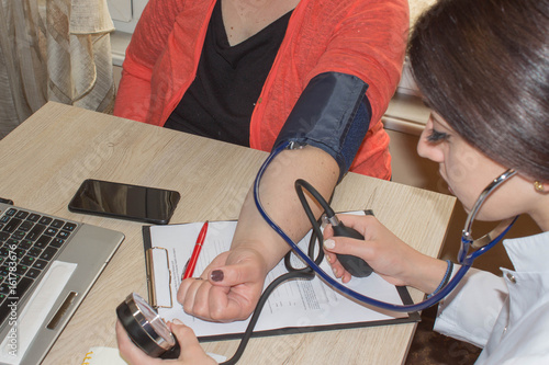 Doctor checking blood pressure of a patient, he is measuring heart pulses with a sphygmomanometer