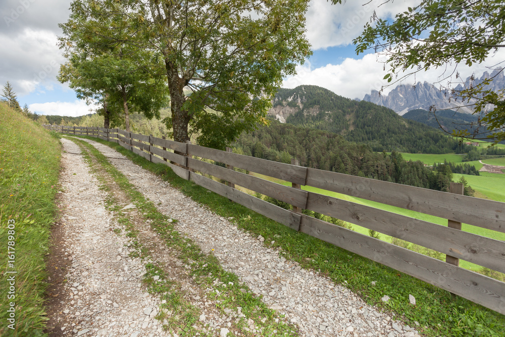 Wooden fence long a secondary mountain white street in Val di Funes