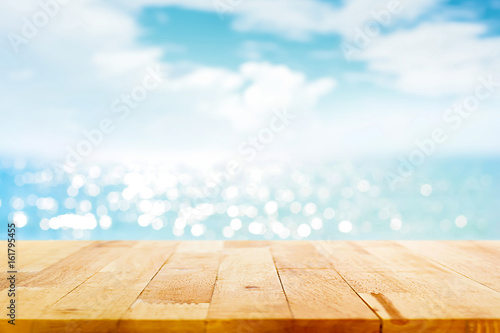 Canvas Print Wood table top on blur sparkling sea water and summer sky background