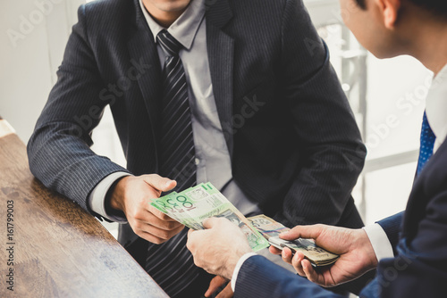 Photography Businessman giving money, Australian dollar bills, to his partner