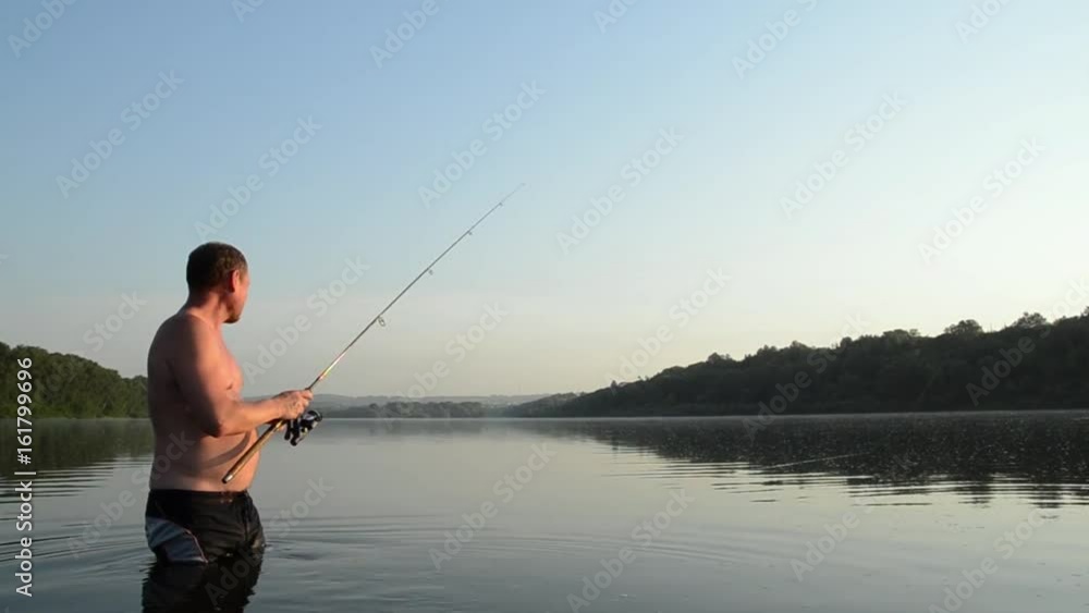 fisherman fishing in a calm river in the morning. Man in fishing gear stending in a river and throws a fishing pole fisherman fishing in a calm river in the morning. Man in fishing gear stending in a river and throws a fishing pole