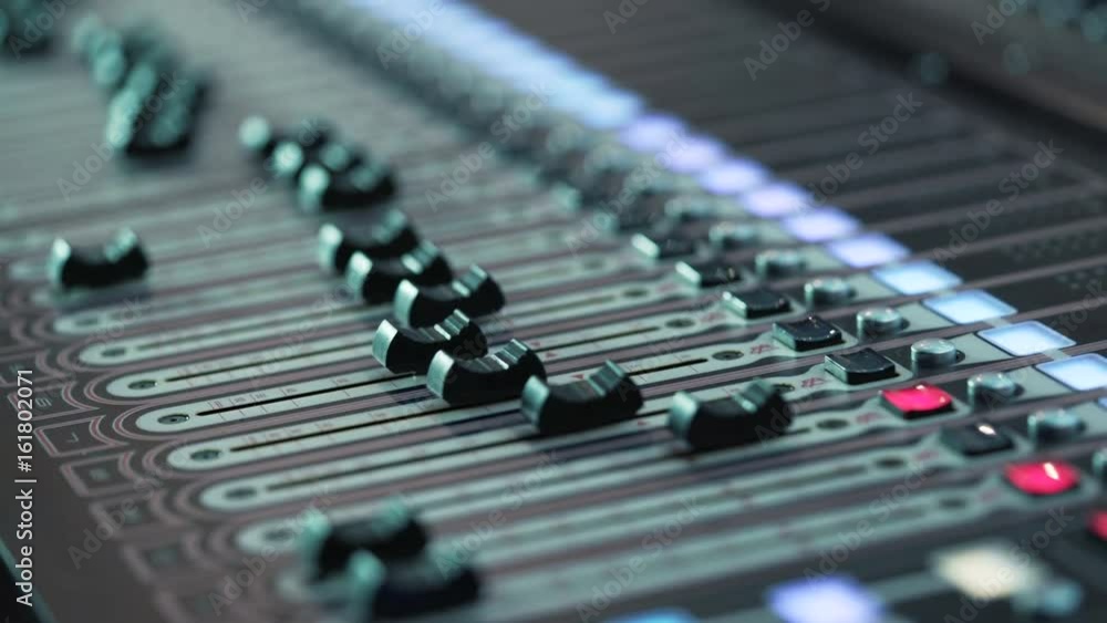 Smooth travel on the console with control buttons. audio mixer in a studio, the automatic knobs moving up and down. Music Mixer desk table in recording studio. shallow depth of field. Close-up Smooth travel on the console with control buttons. audio mixer in a studio, the automatic knobs moving up and down. Music Mixer desk table in recording studio. shallow depth of field. Close-up