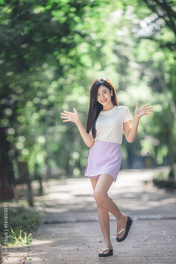 A portrait of a beautiful young asian woman smiling on a park bokeh background A portrait of a beautiful young asian woman smiling on a park bokeh background