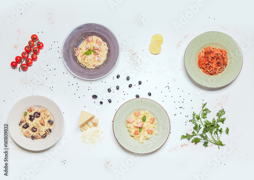 Plates with different kinds of pasta on a white table. view from above.