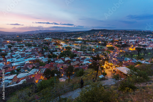 Sunset panorama view of Tbilisi, capital of Georgia country. Metekhi church, Holy Trinity Cathedral (Sameba), Presidential Administration, Bridge of Peace at night with illumination and moving cars. © Konstantin Aksenov