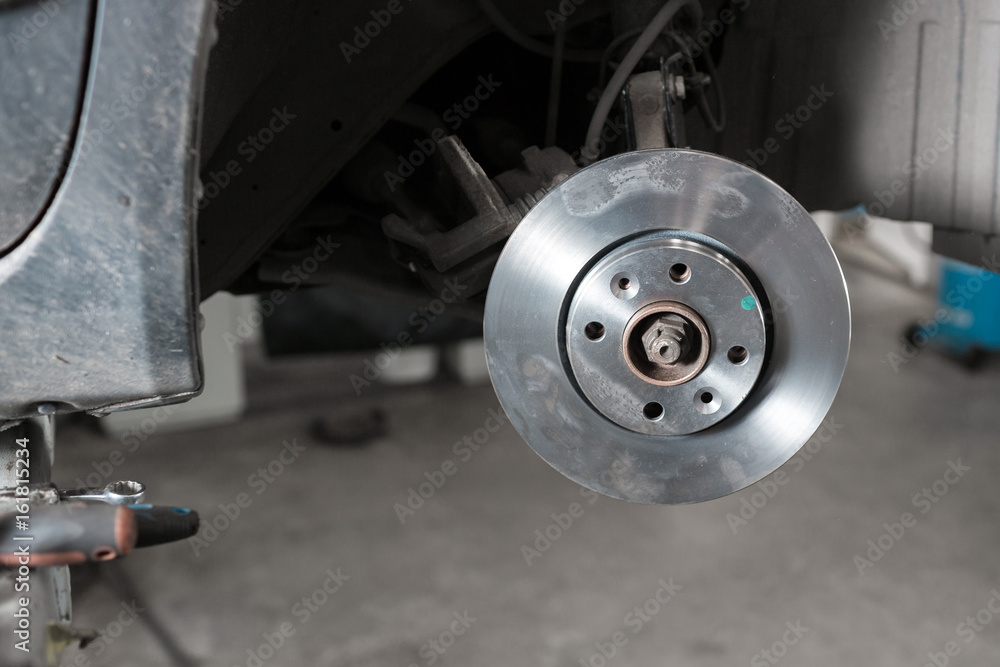 Car mechanic hands replace brakes in garage.
