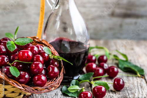 Glass of alcohol tincture made from cherry fruits, liquor in a bottle on rustic background photo