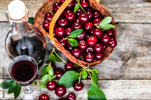 Foto Cherry wine in a glass bottle on wooden table