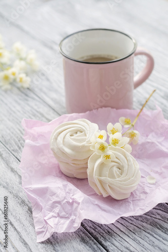 Cup of coffee  homemade marshmallow and jasmine branch on grey wooden table