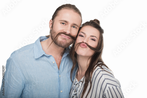 Happy young couple making false moustache from hair and smiling at camera
