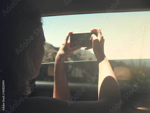 Junges Mädchen sitzt im Auto und macht ein Foto mit ihrem Handy von der Landschaft - Mallorca Spanien