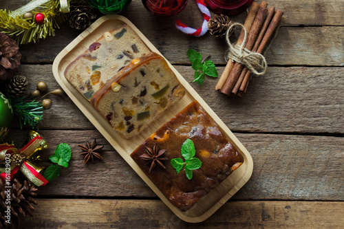 Homemade fruit cake on wood plate. Rum fruit cake with dried fruits made for Christmas celebration. Traditional homemade fruit cake so delicious, rich and moist. Christmas background with copy space.
