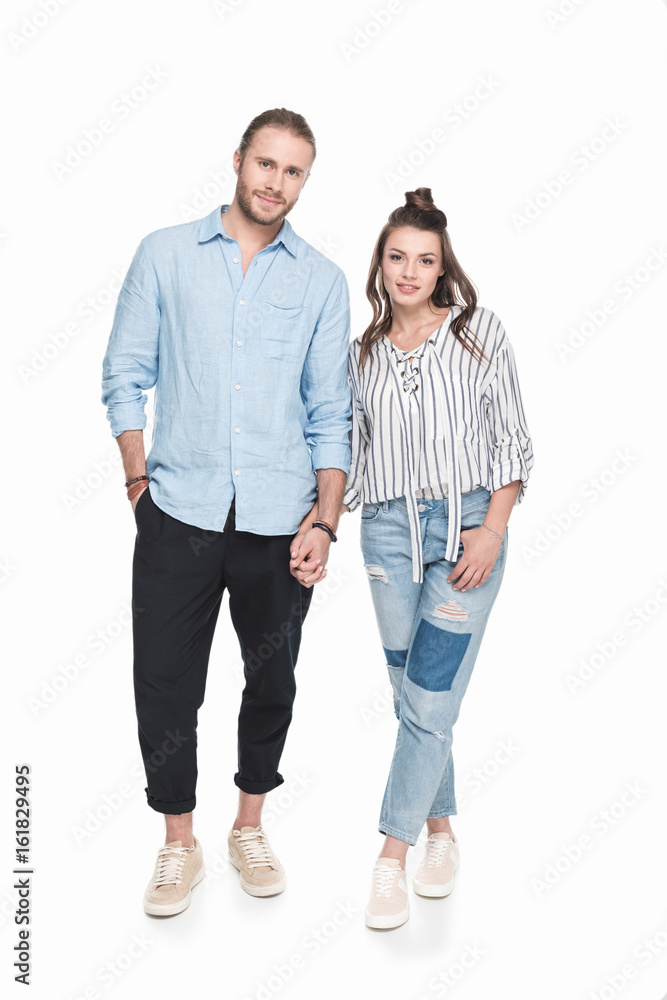 Happy young couple holding hands and smiling at camera Happy young couple holding hands and smiling at camera