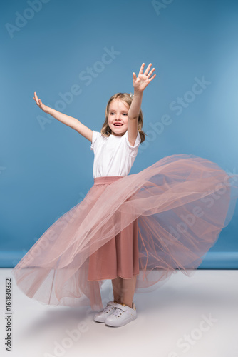 Adorable little girl in pink skirt posing in studio