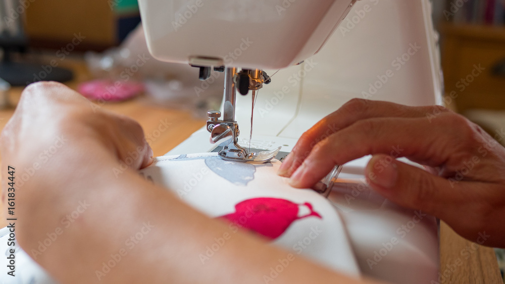 female hand using sewing machine stitching fabic