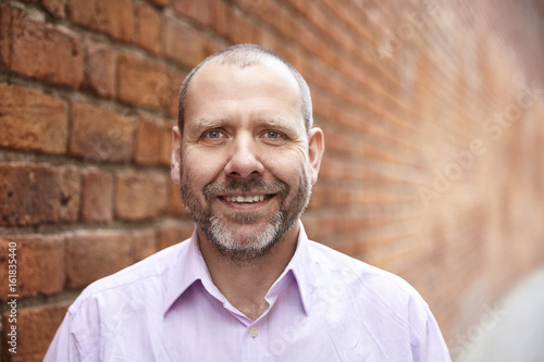 Smiling man against a brick wall