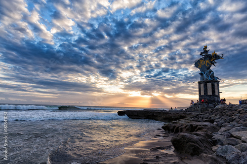 Sun sets behind a sculpture of Gajah Mina on Pererenan beach in Canggu, Bali in Indonesia.