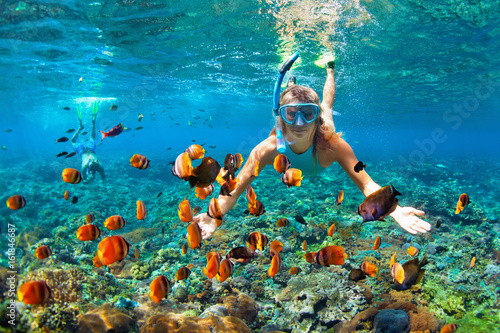 Happy family - couple in snorkeling masks dive deep underwater with tropical fishes in coral reef sea pool. Travel lifestyle, outdoor water sport adventure, swimming lessons on summer beach holiday photo