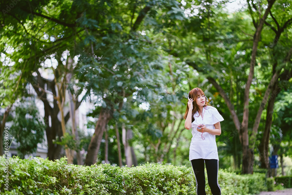 Women with headphones jogging and relaxing stroll in the park happy. Women with headphones jogging and relaxing stroll in the park happy.