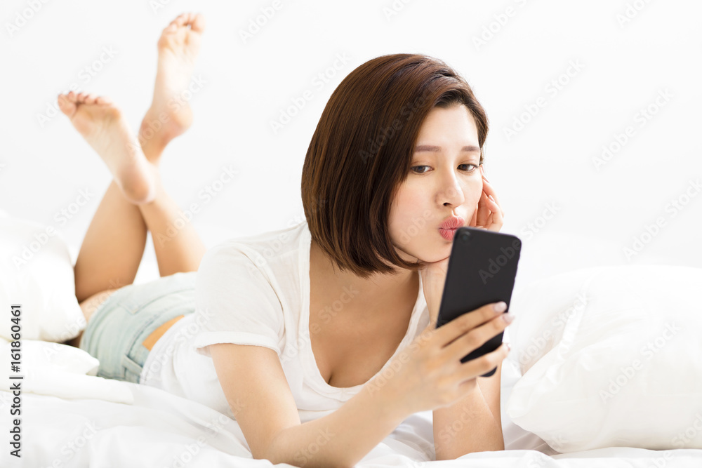Beautiful young woman making selfie in the bed. Beautiful young woman making selfie in the bed.