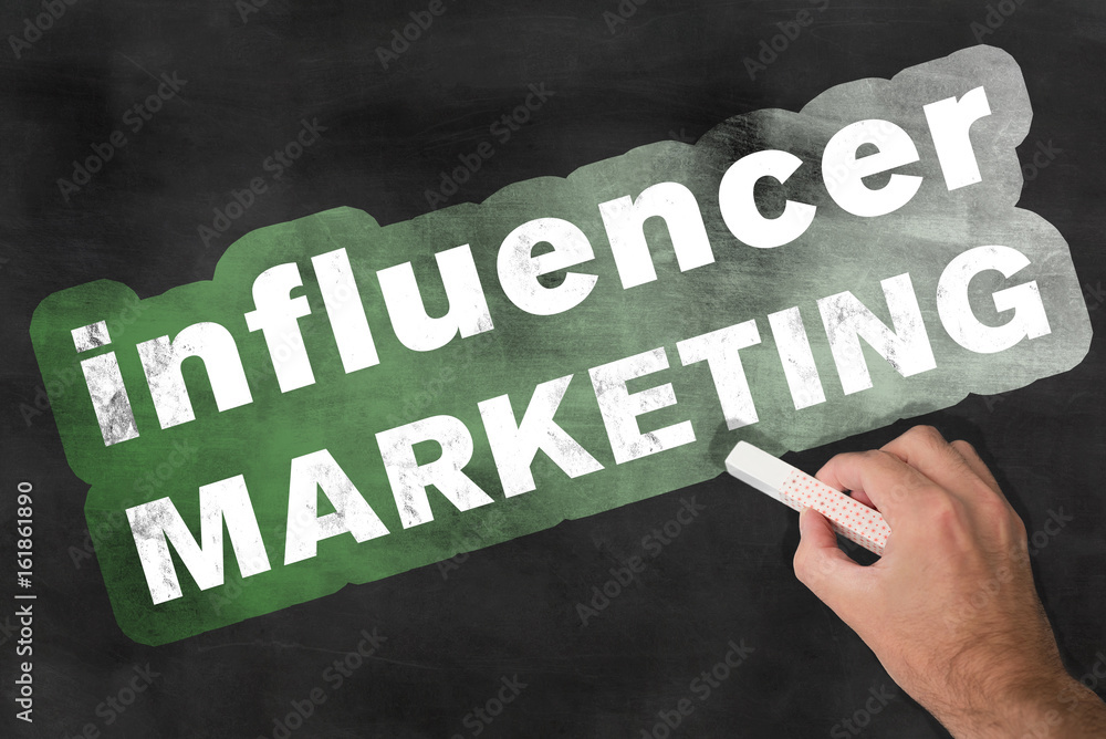 hand holding a piece of chalk after writing the words influencer marketing onto a blackboard concept hand holding a piece of chalk after writing the words influencer marketing onto a blackboard concept