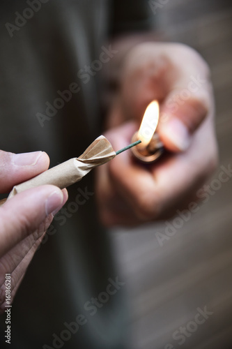 young man lighting a firecracker photo