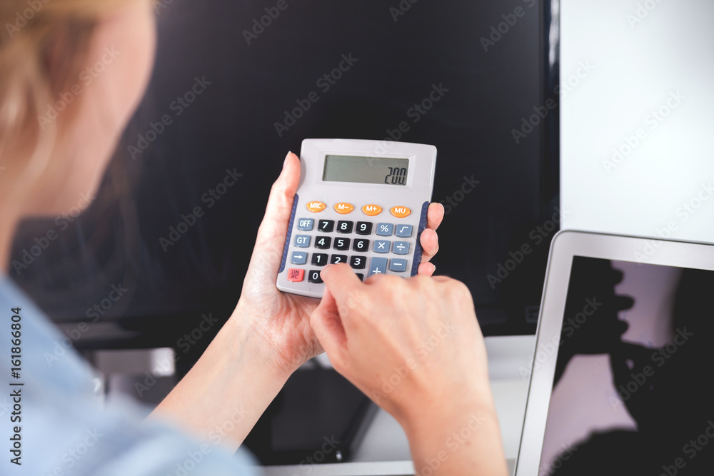 Woman at home office using calculator, calculating budget Woman at home office using calculator, calculating budget
