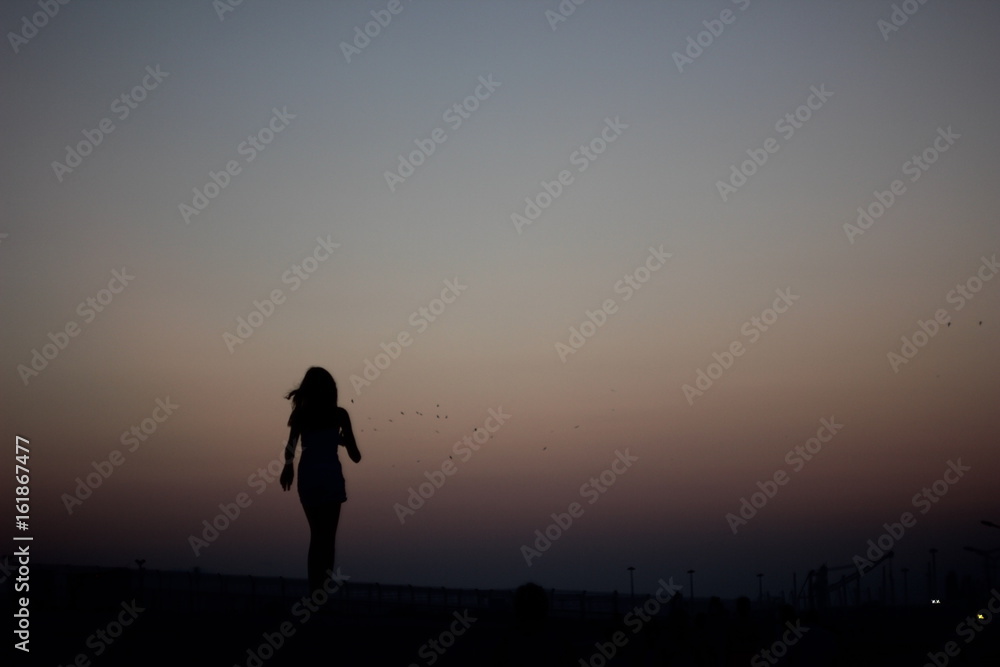 Silhouettes of a girl running on a gradient of a colorful sunset