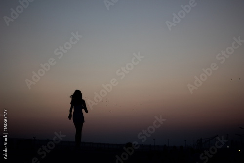 Silhouettes of a girl running on a gradient of a colorful sunset