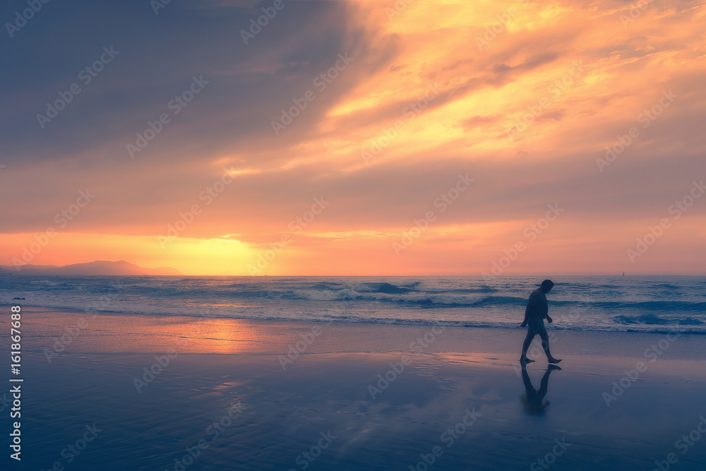 lonely person walking on beach at sunset