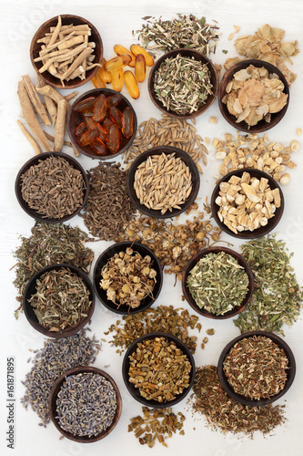 Herb selection to heal sleeping and anxiety disorders in wooden bowls on distressed white background.