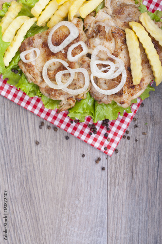  Grilled chicken drumstick on fresh lettuce,  fries and onions