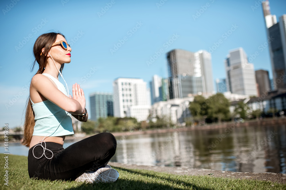 Young woman doing yoga near the river with great view on Frankfurt city Young woman doing yoga near the river with great view on Frankfurt city