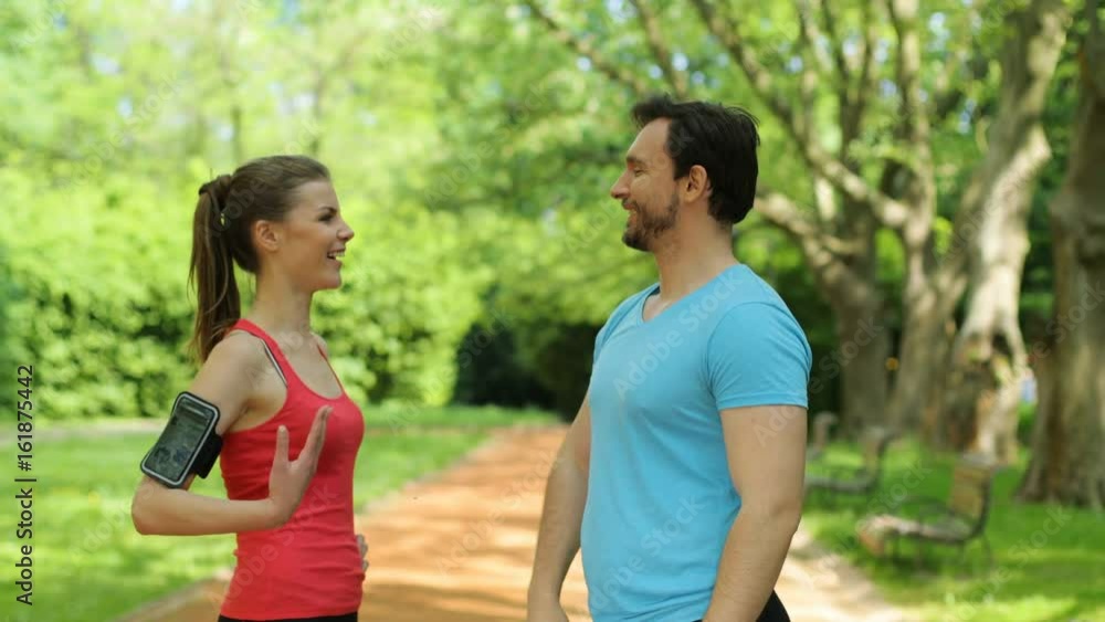 Young sports woman and man giving high fives to each other in the park after training, jogging. Slow motion Young sports woman and man giving high fives to each other in the park after training, jogging. Slow motion