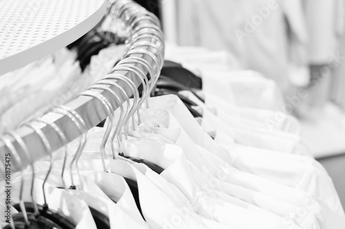 Closeup on shopping clothes hangers on rail in a designer store indoor background. Shallow depth of field of promotional marketing campaign department store design space