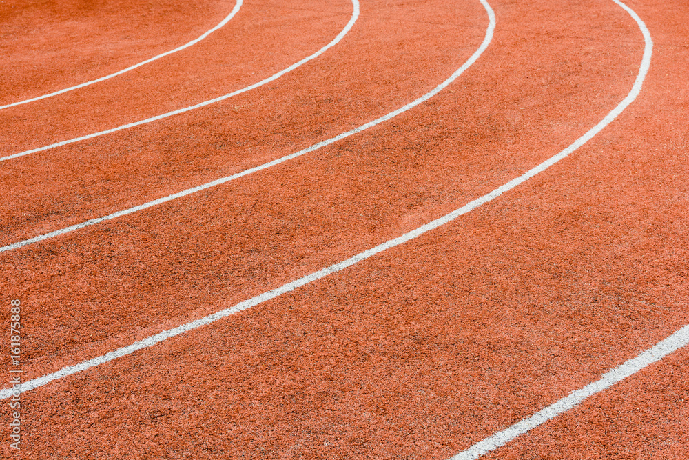 Close-up view of a red athletics track with white lines delimiting the lanes.