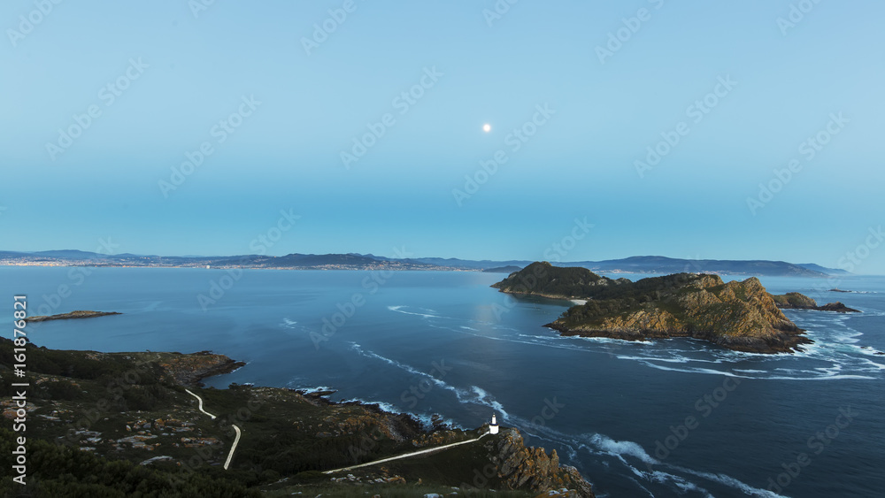 Aerial view of lighthouse cliffs sticking out of blue water of ocean in twilight of San Martiño Island in the Cies Islands, National Park Maritime-Terrestrial of the Atlantic Islands, Galicia, Spain