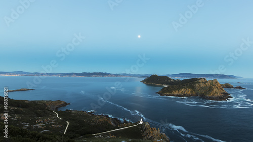 Aerial view of lighthouse cliffs sticking out of blue water of ocean in twilight of San Martiño Island in the Cies Islands, National Park Maritime-Terrestrial of the Atlantic Islands, Galicia, Spain