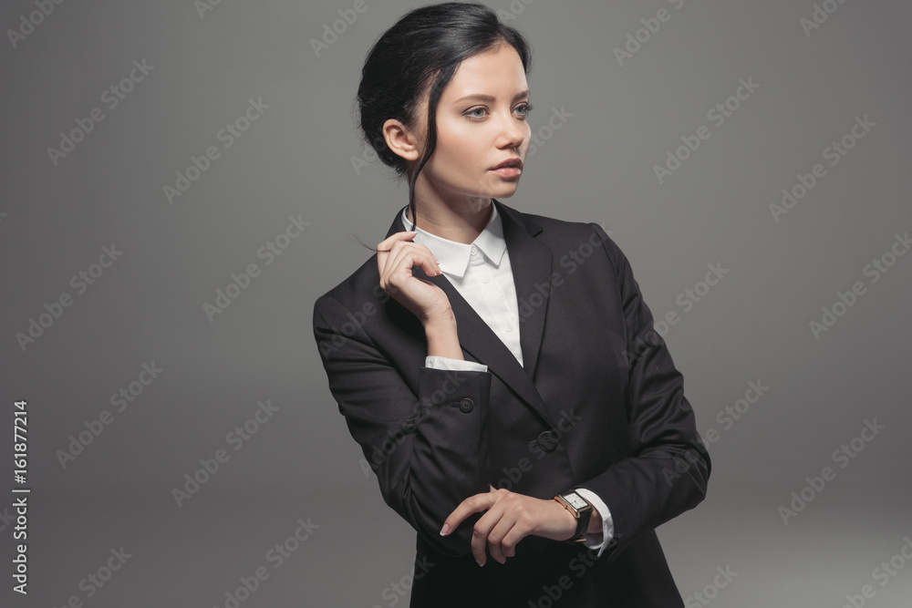confident attractive leader wearing black jacket and looking away, isolated on grey confident attractive leader wearing black jacket and looking away, isolated on grey