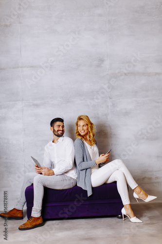 Young couple with tablet and mobile phone on sofa