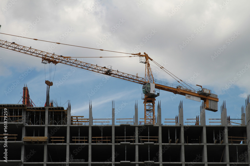 Building crane and building under construction against blue sky.