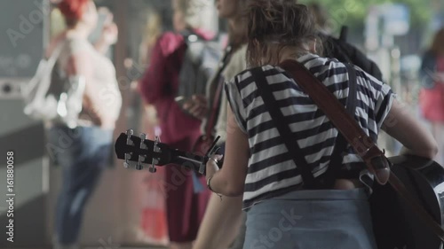 Unidentifiable Young Woman Playing Guitar On A Busy Shopping Street In Berlin In Summer. Slow Motion Shot