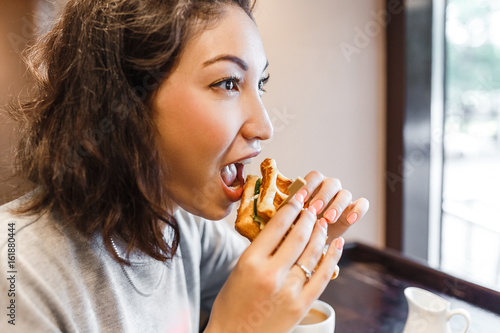 Eastern Woman eating sandwich indoors at cafe