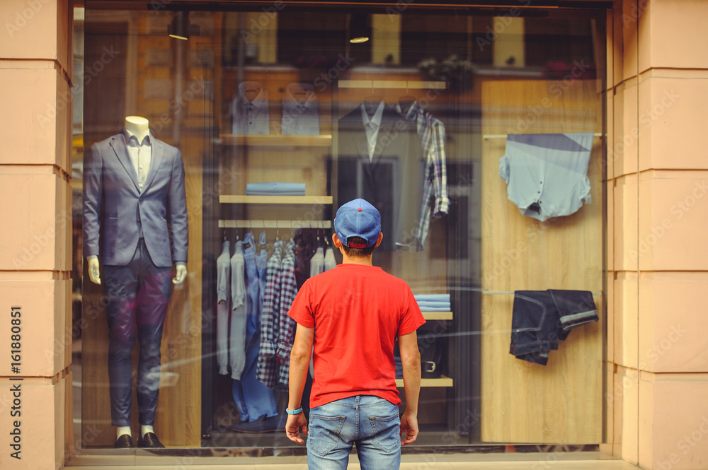 Man in front of shop window with men's clothes Man in front of shop window with men's clothes