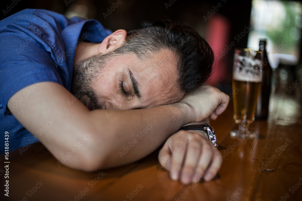 A drunk bearded man holding a glass of beer in his hand and sleeping in the bar
A drunk bearded man holding a glass of beer in his hand and sleeping in the bar