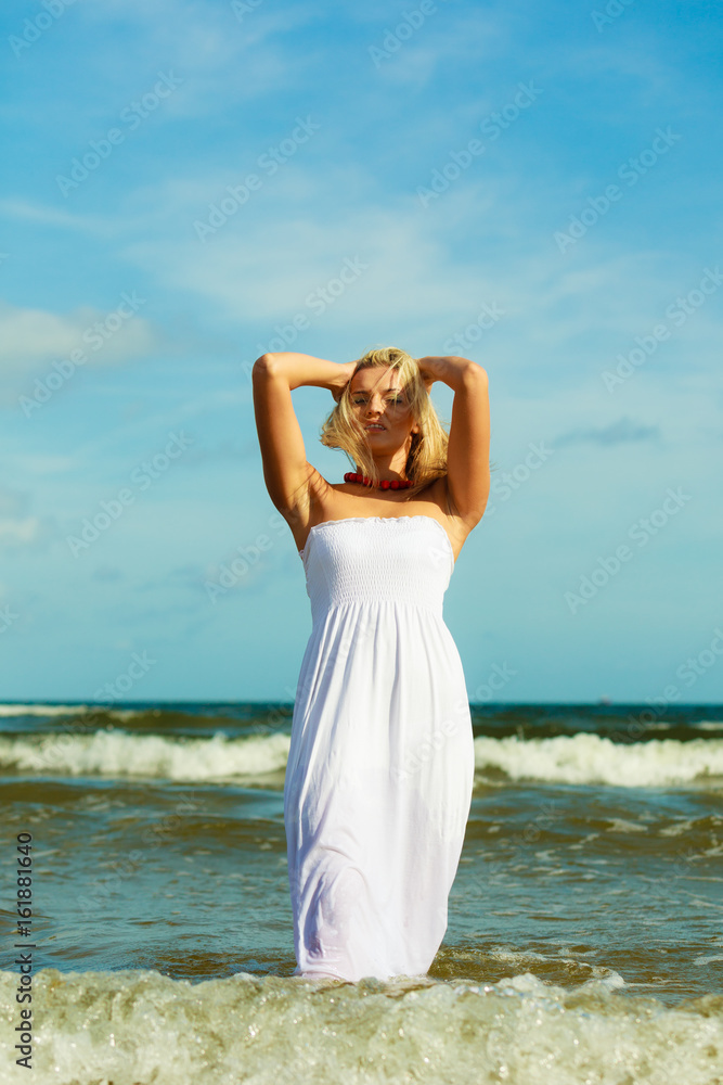 Blonde woman wearing dress walking in water Blonde woman wearing dress walking in water