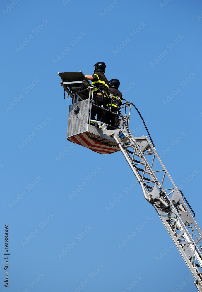 Two intrepid firefighters over the ladder truck metal basket dur Two intrepid firefighters over the ladder truck metal basket dur