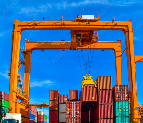 Industrial spreader crane or quay crane discharging a cargo-container onto container truck. Port Logistics. RTG (Rubber Tried Gantry) Cranes loading a container on to a truck photo