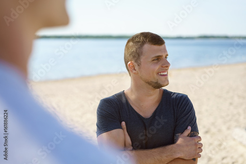 Confident young man on the beach watching with a smile