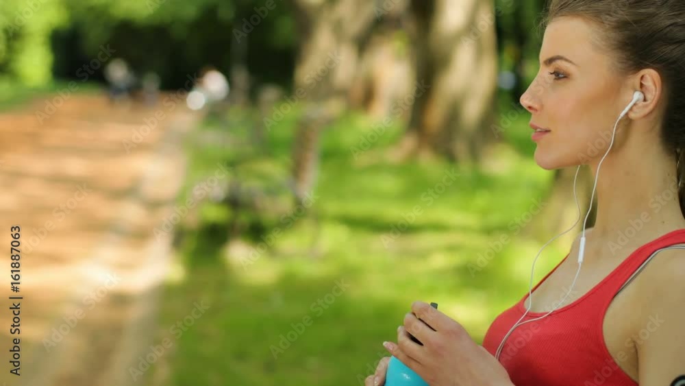Young fitness woman drinking water after training, morning run. woman sitting on a bench. Close up Young fitness woman drinking water after training, morning run. woman sitting on a bench. Close up